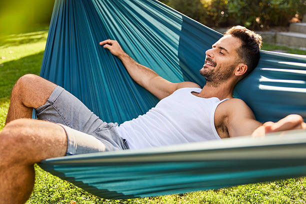 istock Smiling man resting in hammock in backyard 2213464828