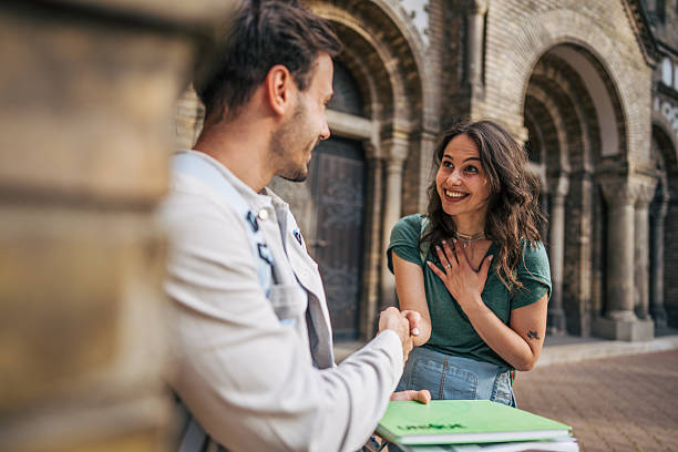 istock Two young students shaking hands in front of university 2213465104