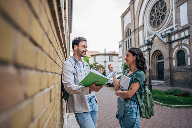 istock Two smiling students talking and learning together outdoors 2213465842