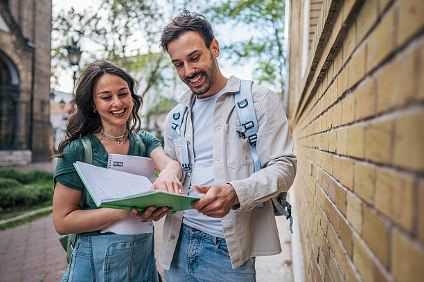istock Two smiling students reviewing notes outdoors near university building 2213466082
