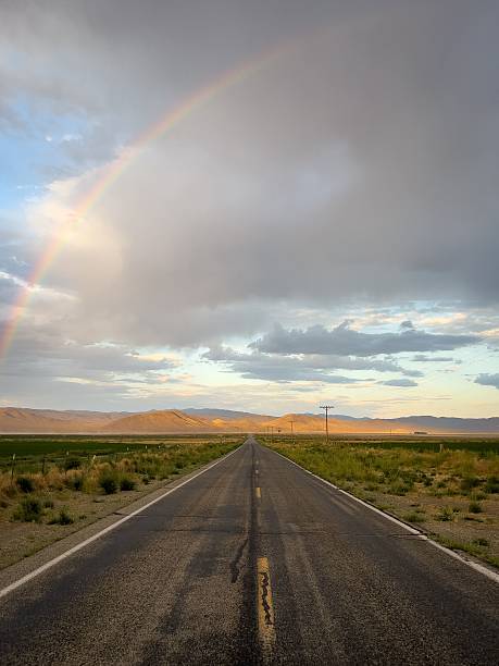 istock Scenic road under a rainbow and cloudy sky. 2213467076