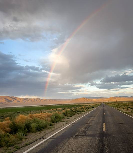 istock Scenic road under a vibrant rainbow and cloudy sky. 2213467078