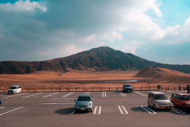 aso, Japan – February 06, 2023: Parking lot at Mt Aso Nakadake Crater with mountain backdrop