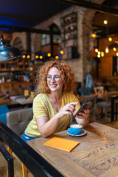 istock Smiling young woman using mobile phone in a cafe 2213468967