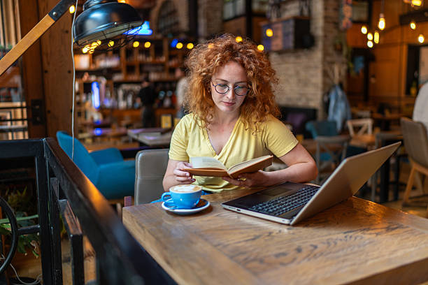 istock Young woman reading a book and drinking coffee in a cafe 2213469272