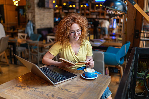 Young woman reading a book and drinking coffee in a cafe