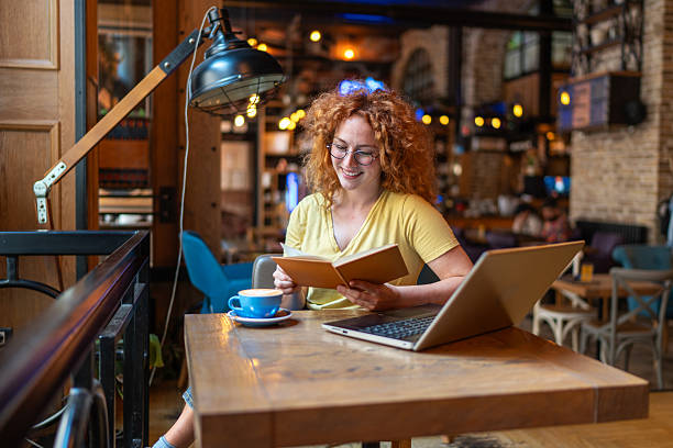 istock Student smiling and reading a book in a coffee shop 2213469279