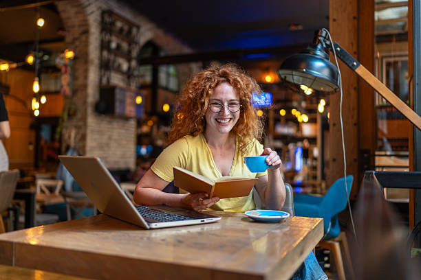 istock Happy student reading a book and drinking coffee in a cafe 2213469291