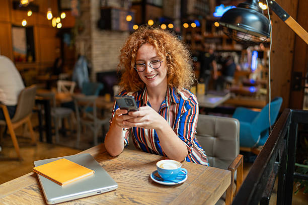 istock Smiling young woman using mobile phone in a cafe 2213469729
