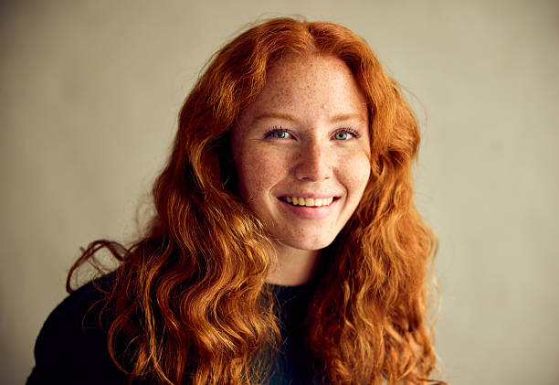 istock Young woman with long wavy red hair in studio, smiling 2213469865