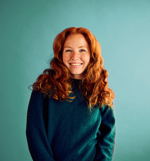 Cheerful young woman with red hair wearing green sweater, front view stock photo
