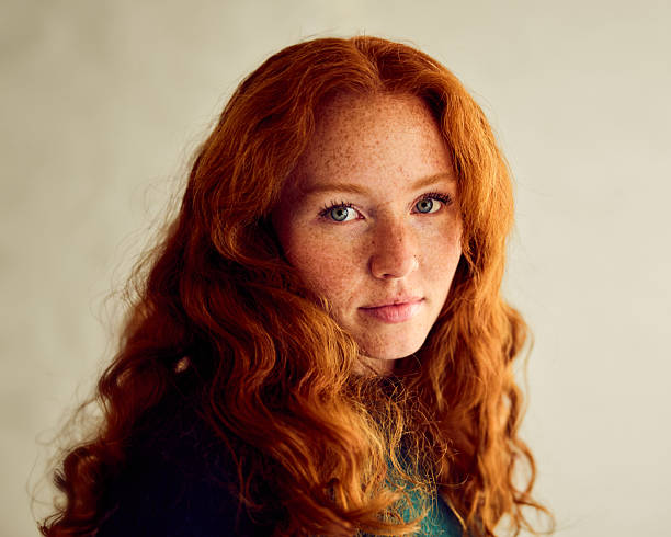 Young woman with long red wavy hair, studio shot