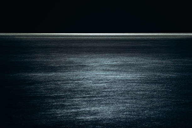 Night seascape in Nice captured with long exposure, creating a smooth, abstract surface and a glowing horizon line.