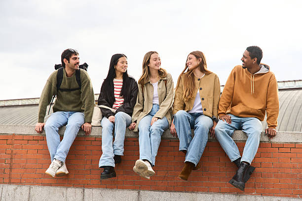 istock Group of diverse students relaxing and chatting on a brick wall, multiethnic people 2213473771