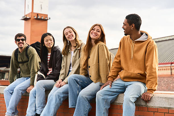 istock Happy students relaxing together sitting on a brick wall 2213474227