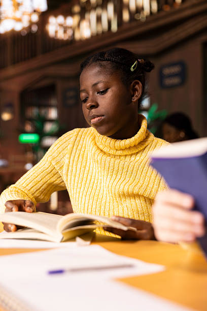 istock Young girl scholar reading literary works and taking notes in a library 2213474933