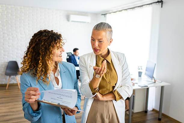 istock Two female colleagues discussing paper work while standing in a modern office 2213475013