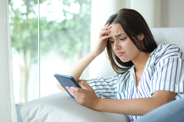 istock Sad woman reading ebook at home 2213477536