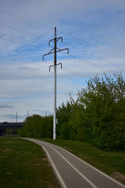 istock High voltage electricity pole and cables near bicycle route path in city area in spring. Pedestrians footpath near big electricity pole in town. 2213477580