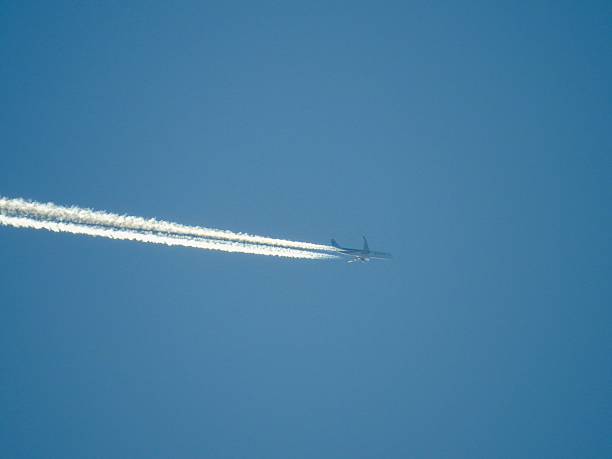 istock Airplane soaring high with contrails in clear sky. 2213479860
