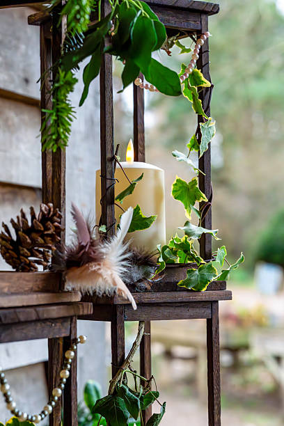 istock Rustic Candle Display with Ivy, Feathers, and Pinecone on Wooden Frame Outdoors 2213480839