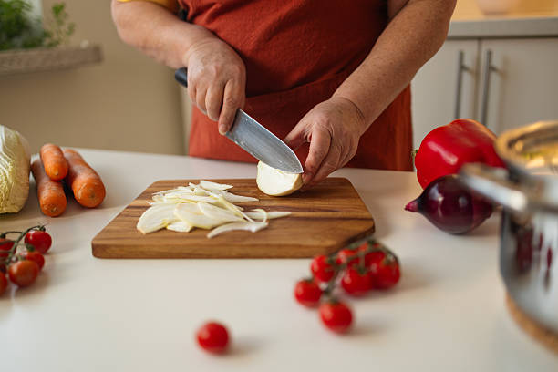 istock Person Slicing Onion in Kitchen for Cooking 2213483273