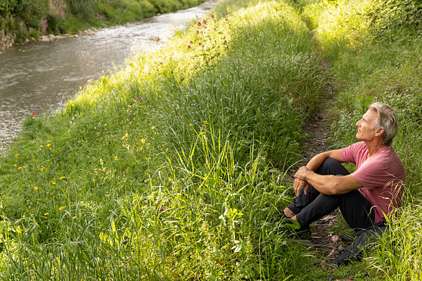 Mature man pauses by water's edge in springtime, Liguria