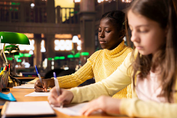 istock Diverse teens studying at a library table with textbooks and pens 2213483936