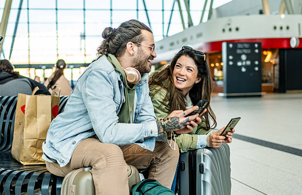 istock Happy tourists couple using mobile phone at the train station 2213489274