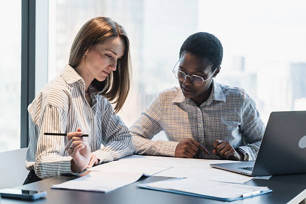 Two Business Women Discussing Documents in a Modern Office Setting
