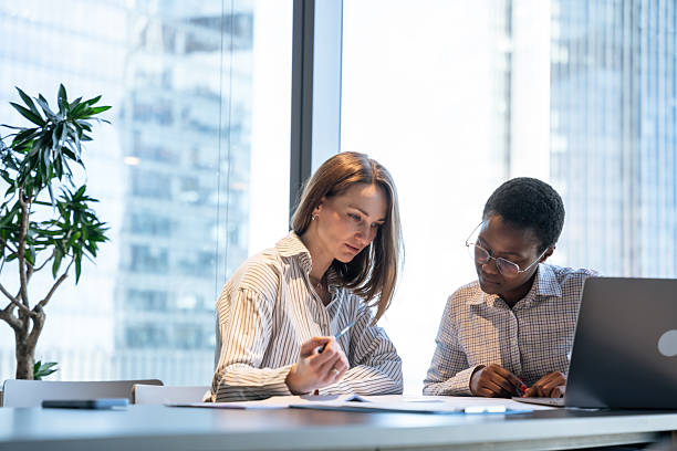 istock Two Business Women Examining Documents in a Modern Office Setting 2213499630