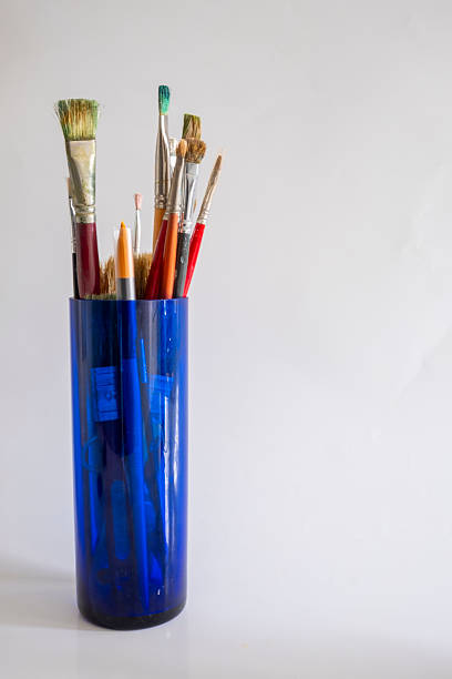 Oil paint brushes of various sizes in a blue glass container