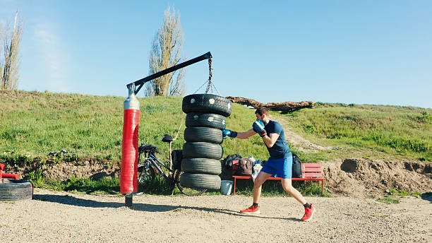 istock Young man practicing boxing outdoors with a homemade punching bag 2213503926
