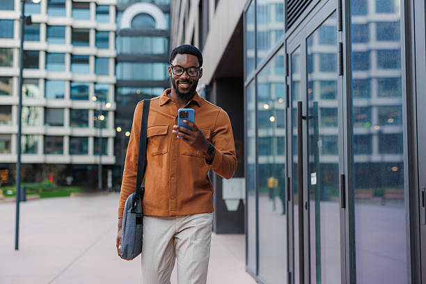 istock Man walking outside using his phone in a business area 2213505546