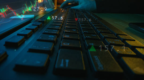 istock Up Close with a Person's Hands Working on a Keyboard Connected to a Desktop Computer. Graphics Present Upward and Downward Trending Stock Market Icons. Economy, Finance and Investing Concept 2213506283