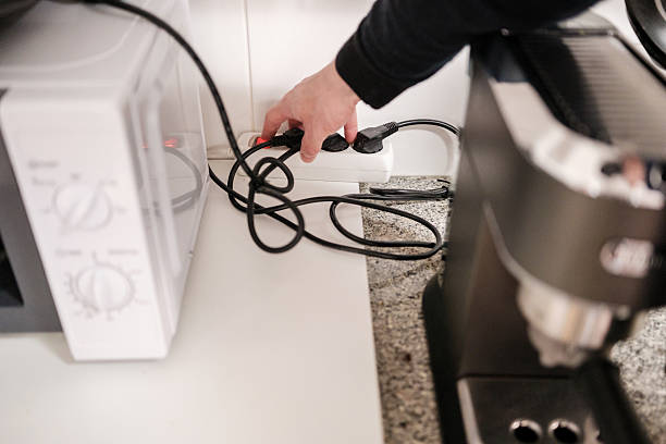 istock Person plugging appliance into overloaded power strip in kitchen 2213509370