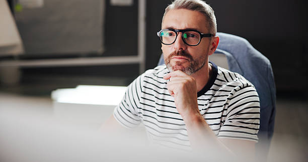 istock Online, night and mature man with computer, office and creative for web design with software or reading. Overtime, graphic designer and person with glasses in business, deadline and tech for project 2213509655