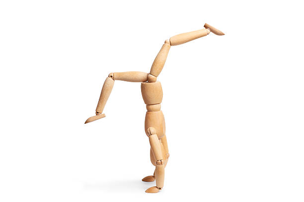 A wooden mannequin doing a handstand on white background with copy space