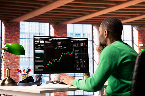 istock Investor looking at stock exchange graphs on computer monitor 2213510563
