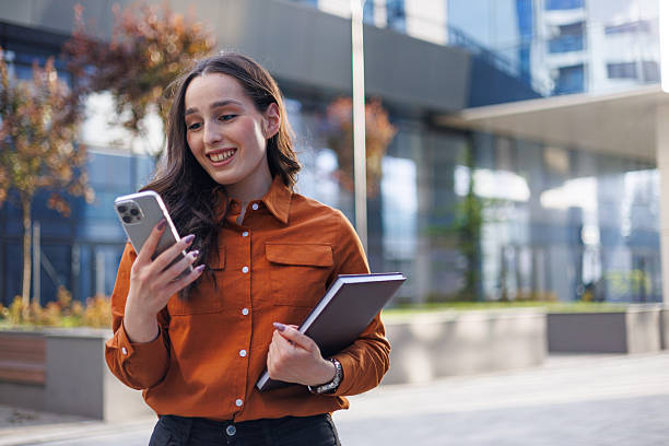 istock Young businesswoman is using a smartphone and holding a notebook while going to work 2213519592
