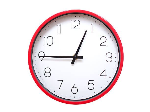 Minimalist Round Wall Clock Showing 00:45 or 12:45. Thin Black Numerals on White Wood Background.