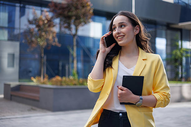 istock Young businesswoman holding tablet and talking on the phone while walking outside office building 2213523607