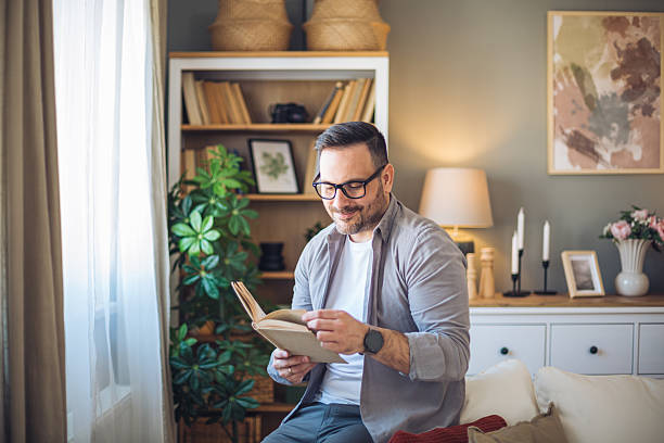 istock Man reading a book and relaxing on the sofa at home 2213527512