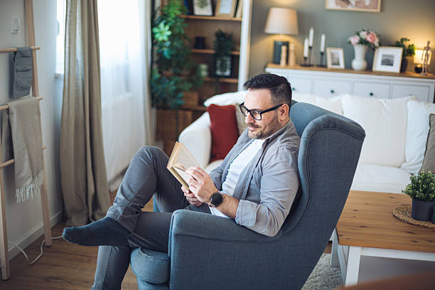 Mid adult man enjoying a quiet moment reading in a comfortable, well-decorated living room