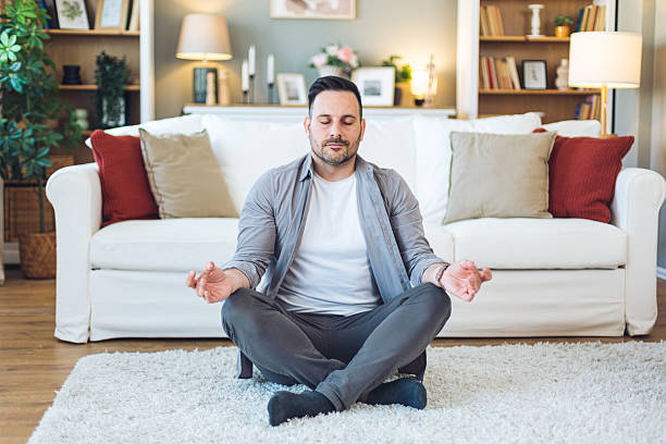 istock Young man meditating in living room on white carpet 2213530045
