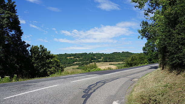 Curving Rural Road Through French Countryside Under Clear Blue Sky