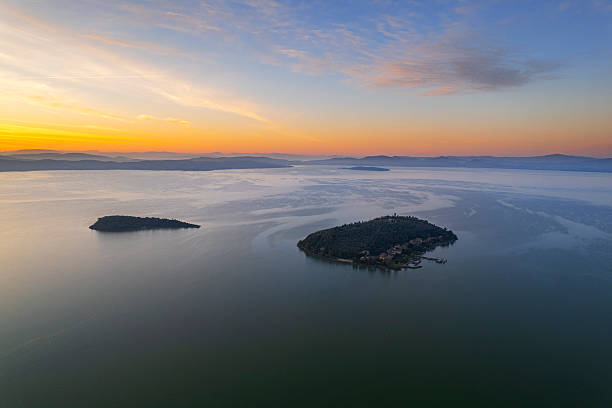 Idyllic aerial view of two small islands in the middle of a lake at sunrise, Trasimeno lake, Perugia province, Umbria, Italy