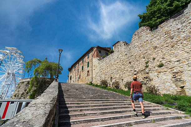 View of a tourist climbing empty stairs to visit a traditioanl village, Castiglione del Lago, Perugia, Trasimeno lake, Umbria, Italy