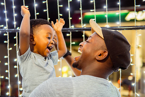 istock Father and son laughing together under christmas lights 2213539065