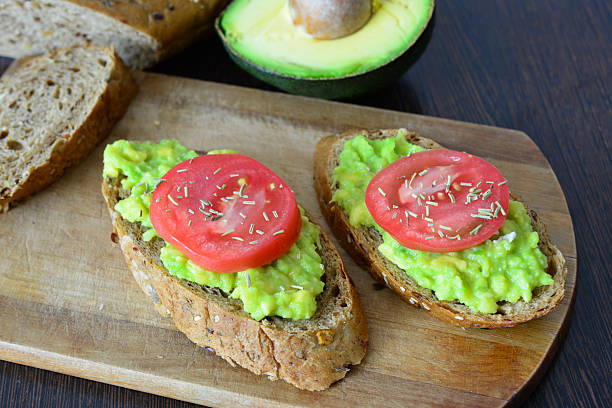 istock mashed Avocado with Tomato Slices on the slices of bread on cutting board 2213540507